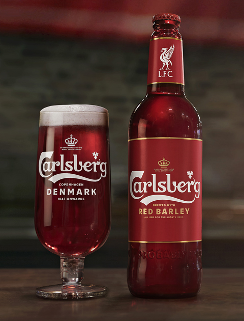 carlsbergs red barley beer in a glass and bottle standing on a table